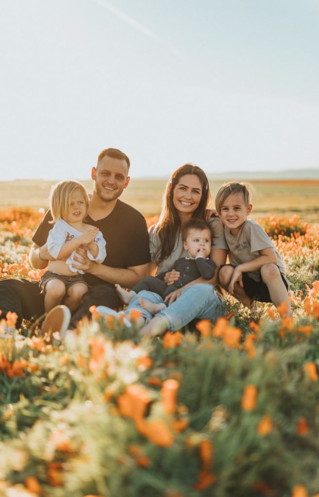 a family sitting in a field of flowers