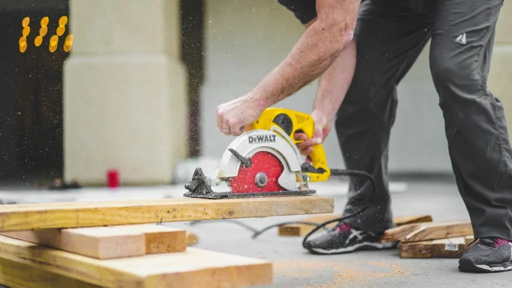 a man cutting a wood plank