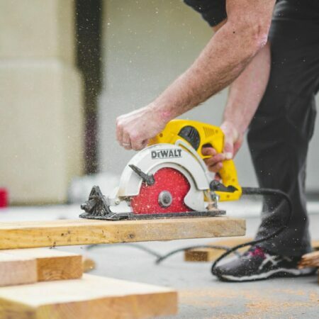 a man cutting a wood plank