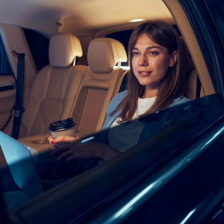 Smiling woman with coffee cup sitting in car